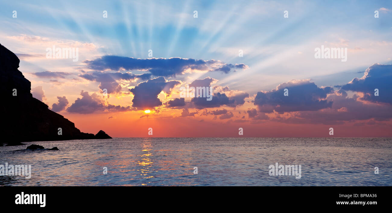 Wunderschöne Landschaft von der aufgehenden Sonne und Berge. Strahlen dringen in den Wolken. Stockfoto