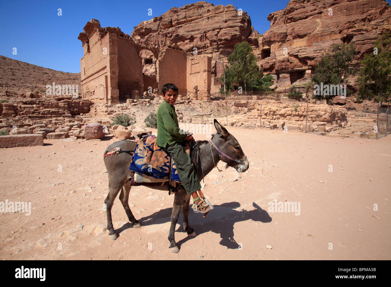 Kinder reiten einen Esel vor dem Tempel Dushares (Qasr al-Bint), Petra, Jordanien Stockfoto