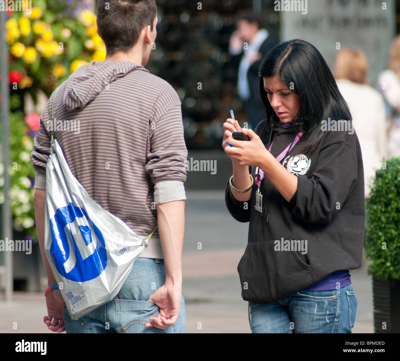 Ein weiblicher Liebe Arbeiter hält einen Mann in einer Glasgow-Straße um ihn für eine monatliche Spende Lastschriftverfahren anmelden. Stockfoto