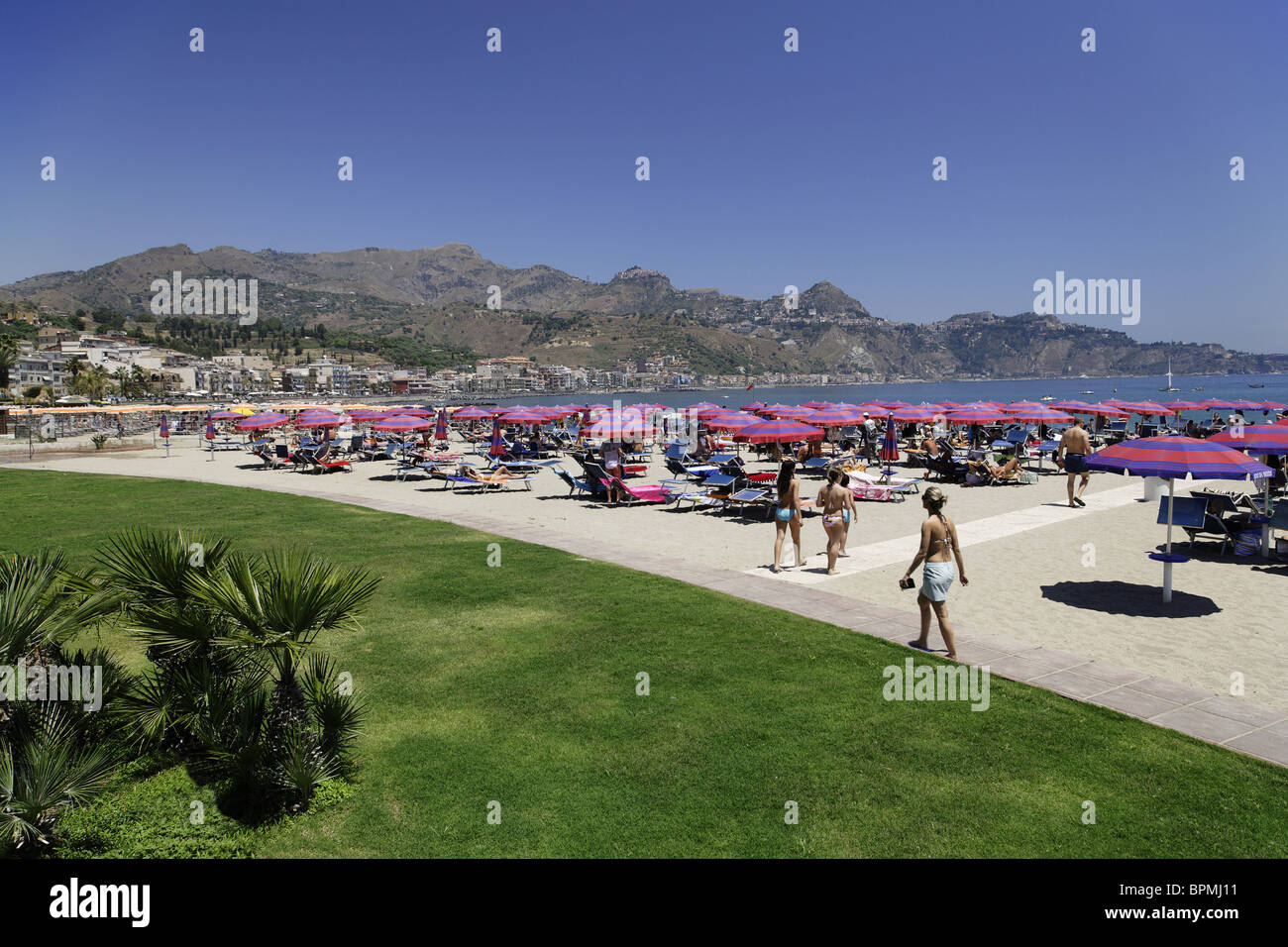 Leute, Sonnenbaden am Strand, die Bucht von Giardini Naxos, Taormina im Hintergrund, Sizilien, Italien Stockfoto