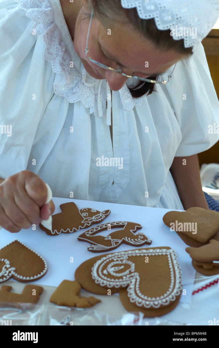Eine Frau schmückt ein Pernik Biskuit mit traditionellen Mustern auf eine fertige Stall in der Slowakei Stockfoto