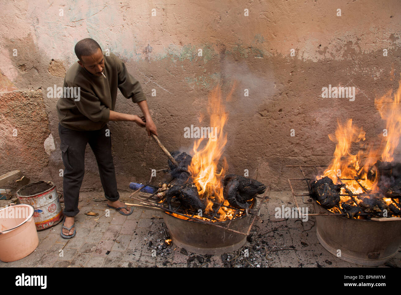 Ein Mann schürt die bbq's am Tag der Eid al-Adha, Marrakesch, Marokko Nordafrika Stockfoto