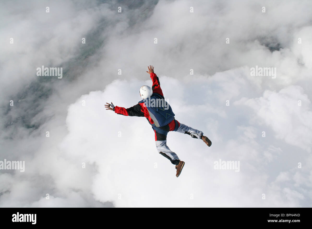 Fallschirmspringer im freien Fall mit Wolken unter ihm Stockfoto