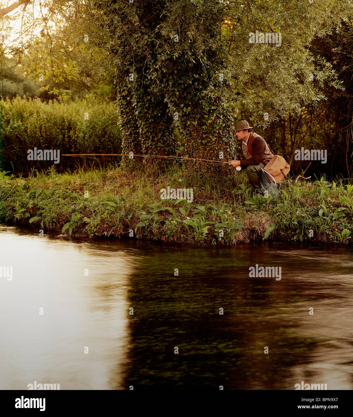 Ein Mann allein an einem Flussufer Angeln Stockfoto