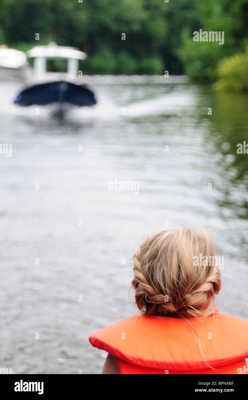 Junge blondes Mädchen tragen Leben west sieht am Fluss und Boot Stockfoto