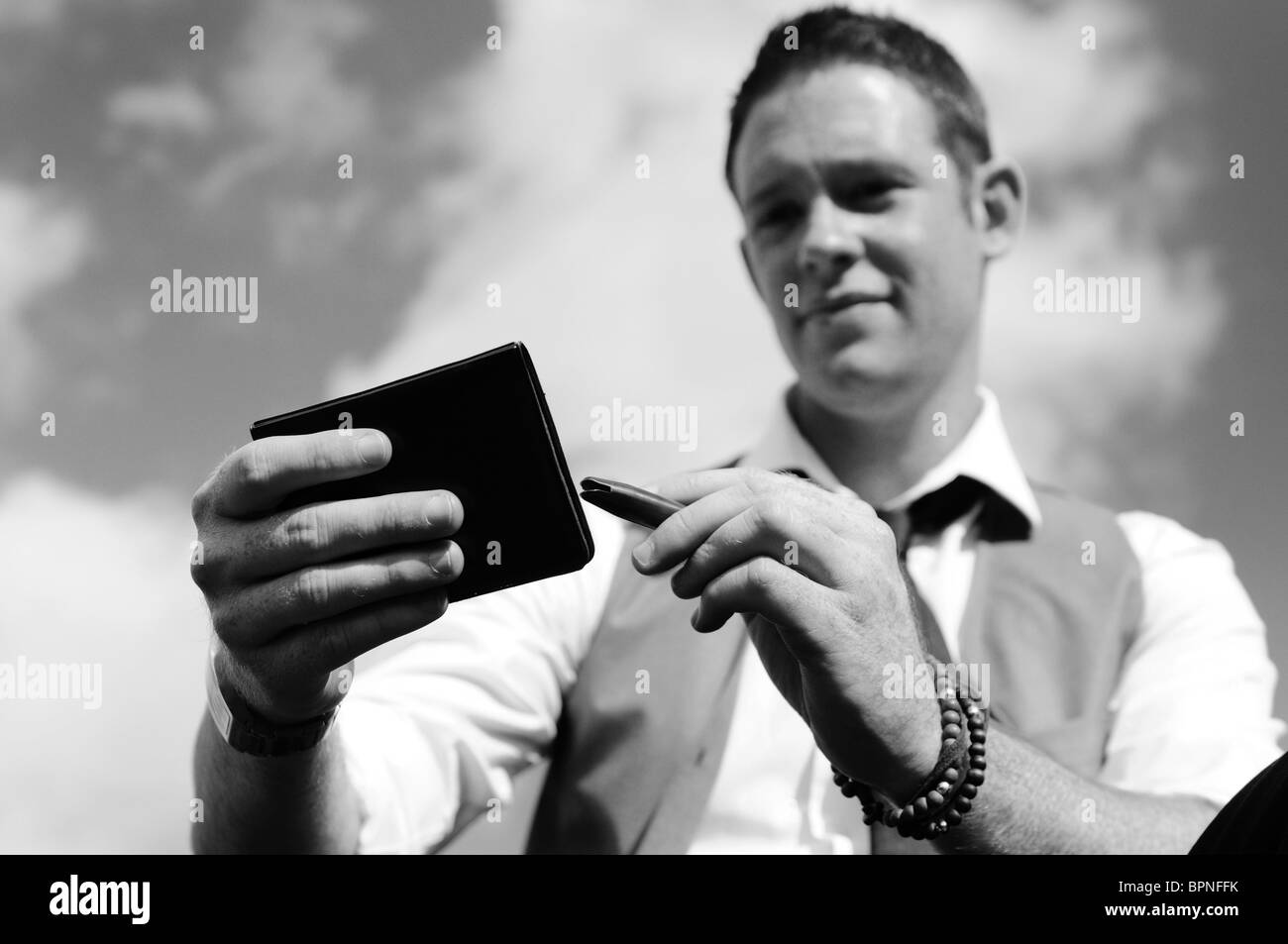 junger weißer Mann mit Ingwer Haar Sitz außerhalb mit Notizblock und Stift denken in schwarz und weiß Stockfoto