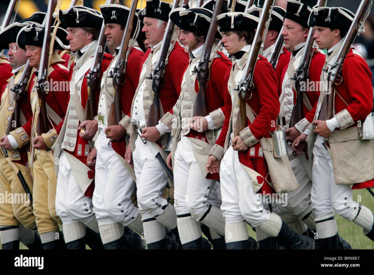Rotröcke aus dem amerikanischen Unabhängigkeitskrieg 1775-1783. Brown Bess Musketen, Schnauze laden Steinschloss glatte Bohrungen Festival Geschichte 2010, Kelmarsh Hall, Northamptonshire. Re-Anactors erleben Sie britische Geschichte von den Römern bis zum zweiten Weltkrieg Stockfoto