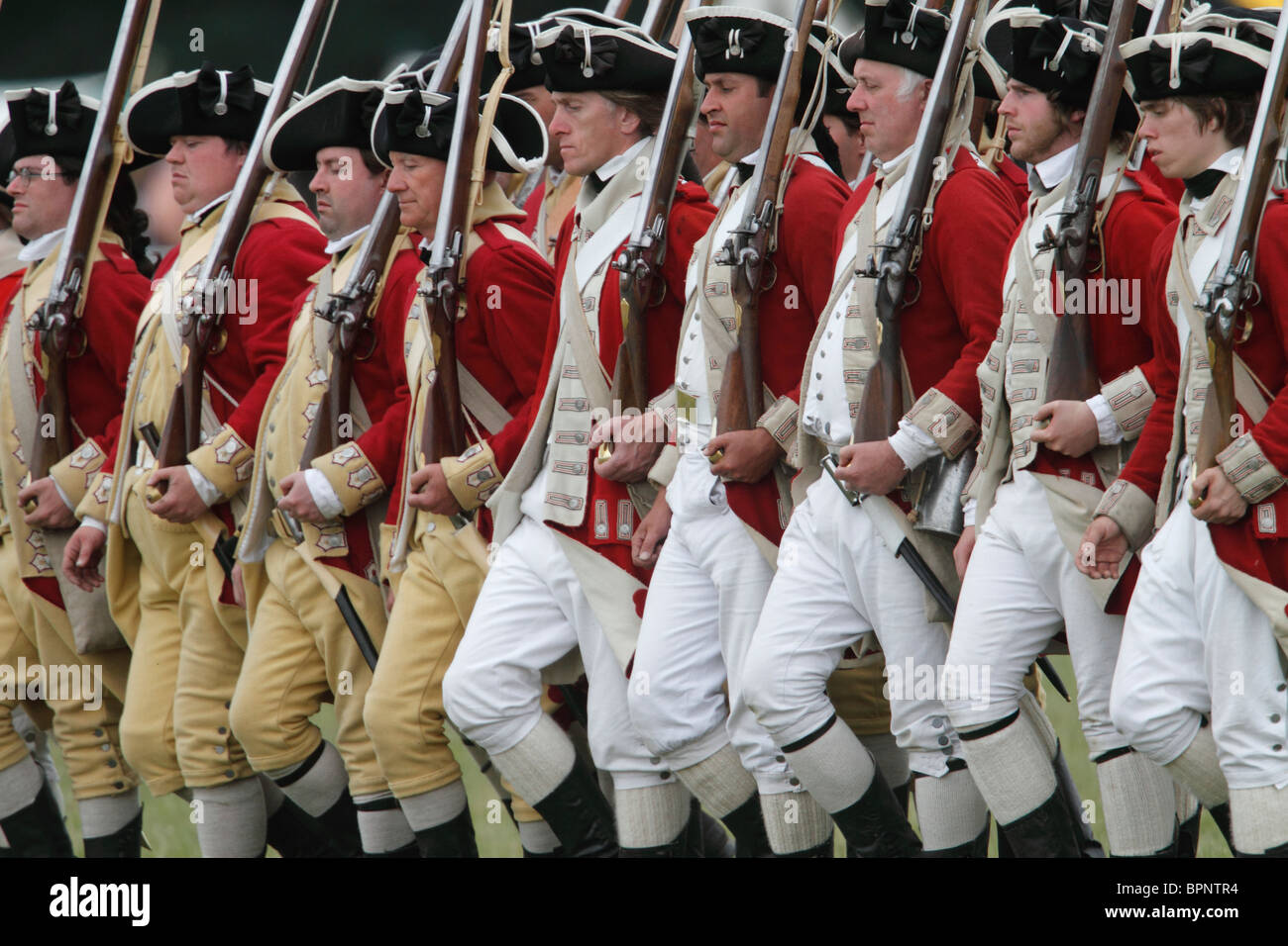 Rotröcke aus dem amerikanischen Unabhängigkeitskrieg 1775-1783. Brown Bess Musketen, Schnauze laden Steinschloss glatte Bohrungen Festival Geschichte 2010, Kelmarsh Hall, Northamptonshire. Re-Anactors erleben Sie britische Geschichte von den Römern bis zum zweiten Weltkrieg Stockfoto