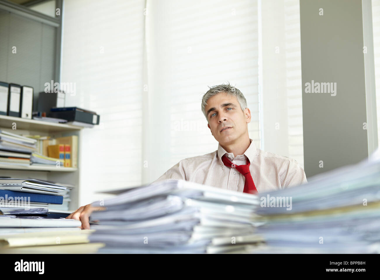 Mann im Büro mit Haufen Papierkram Stockfoto