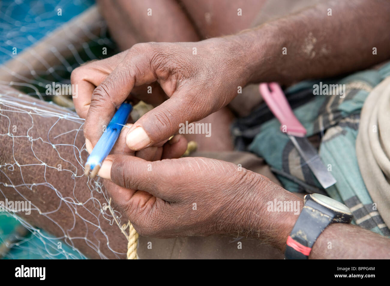 Indische Fischer ist ein Fischernetz auf seinem Boot im Fisherman Village in Puri, Orissa, Indien reparieren. Stockfoto