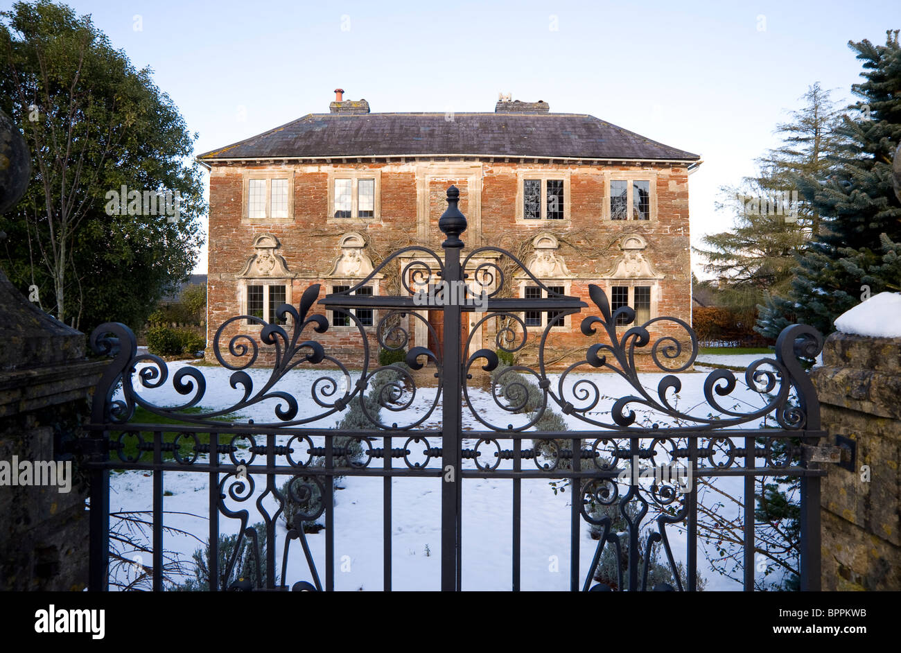 Englische Traditionshaus im Schnee, mit reich verzierten Tor: Tilly Manor, West Harptree Stockfoto