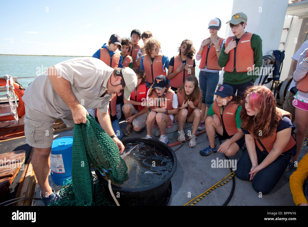 Meeresbiologe stellt Wels in einem Tank, Mittelschüler / innen an Bord eines Forschungsschiffes während der Exkursion der Klasse zu zeigen Stockfoto