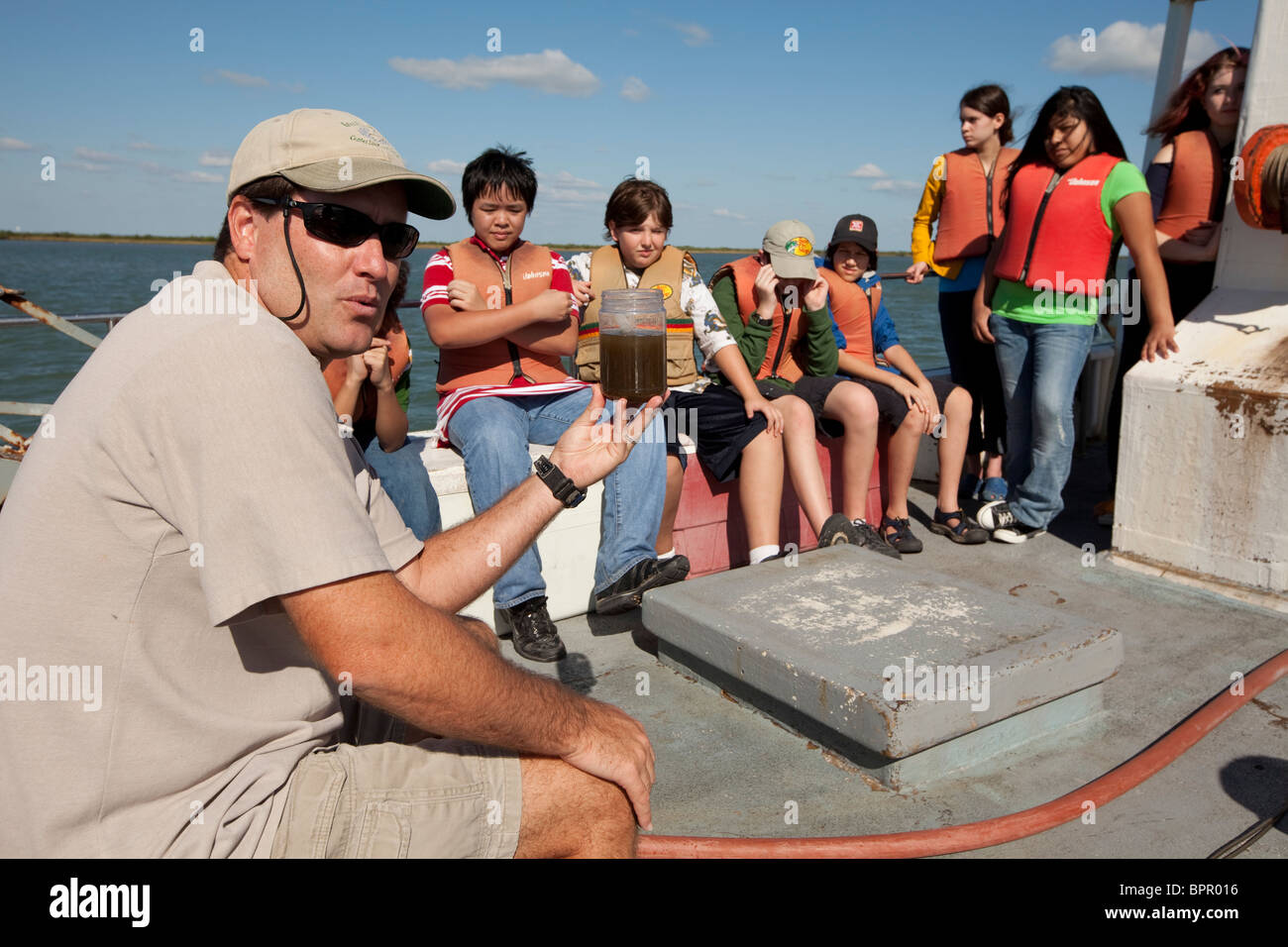 Meeresbiologe hält Behälter trüben Seewasser während des Sprechens in junior high Kinder an Bord Forschungsschiff im Golf von Mexiko Stockfoto