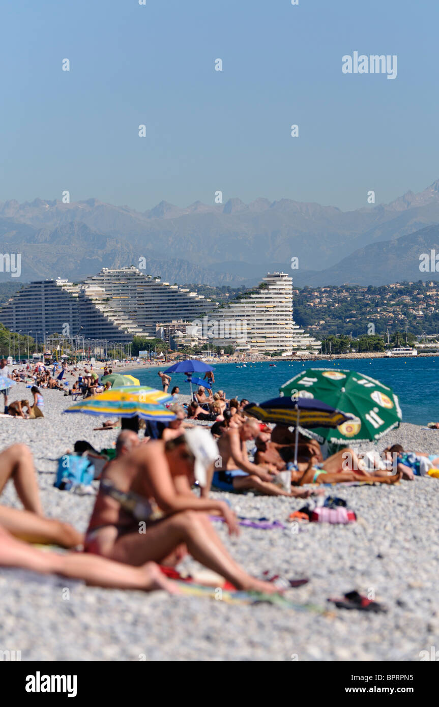 Menschenmassen am Kiesstrand in Antibes und Villeneuve Loubet, mit Blick auf Nizza. Stockfoto