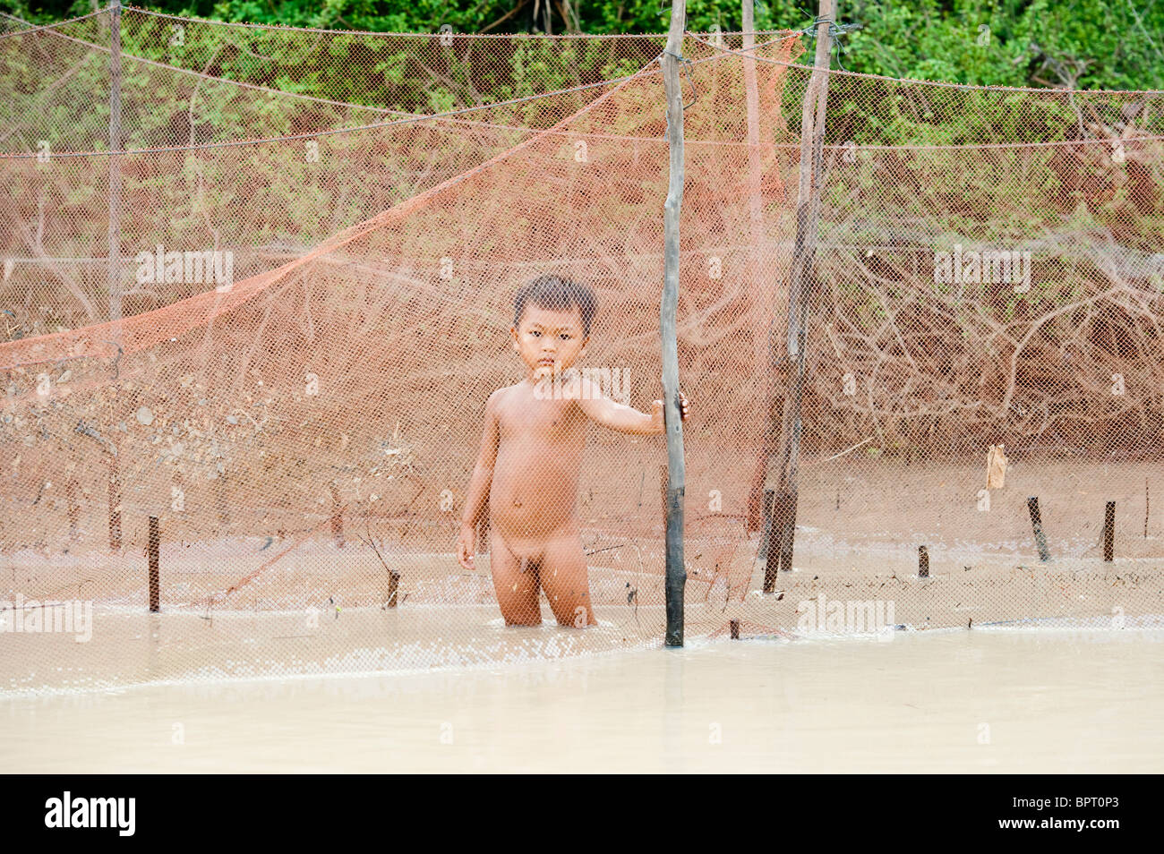 Kind hinter einem Netz in einer Fischfarm, Tonle Sap See in der Nähe von Siem Reap, Kambodscha Stockfoto