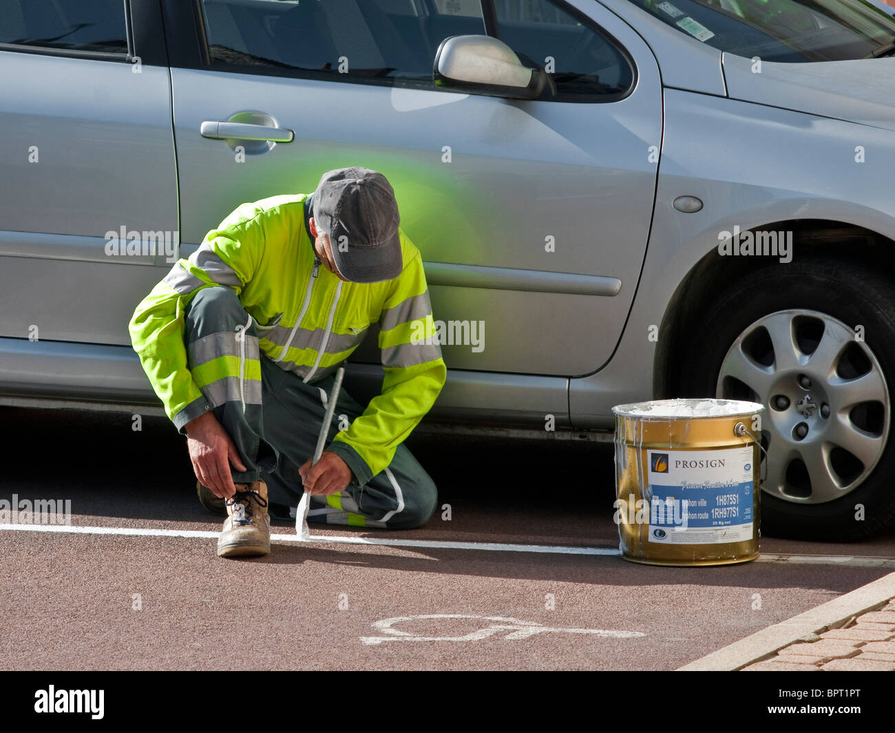 Des Rates Arbeiter malen weiße Linie auf Parkplatz Bucht - Frankreich. Stockfoto