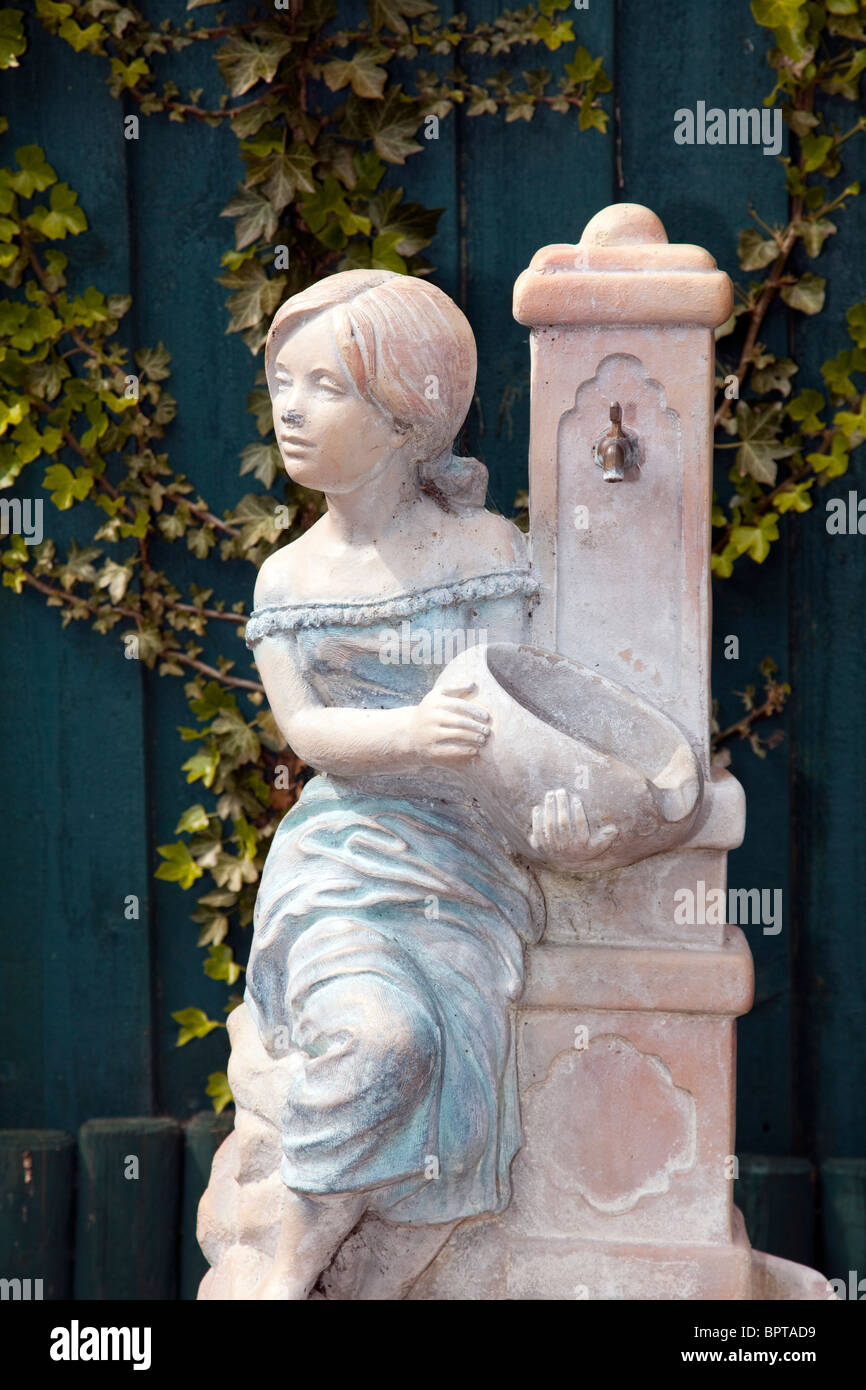 konkrete Statue Wasserspiel junge Mädchen halten Gericht unter fließendem Stockfoto