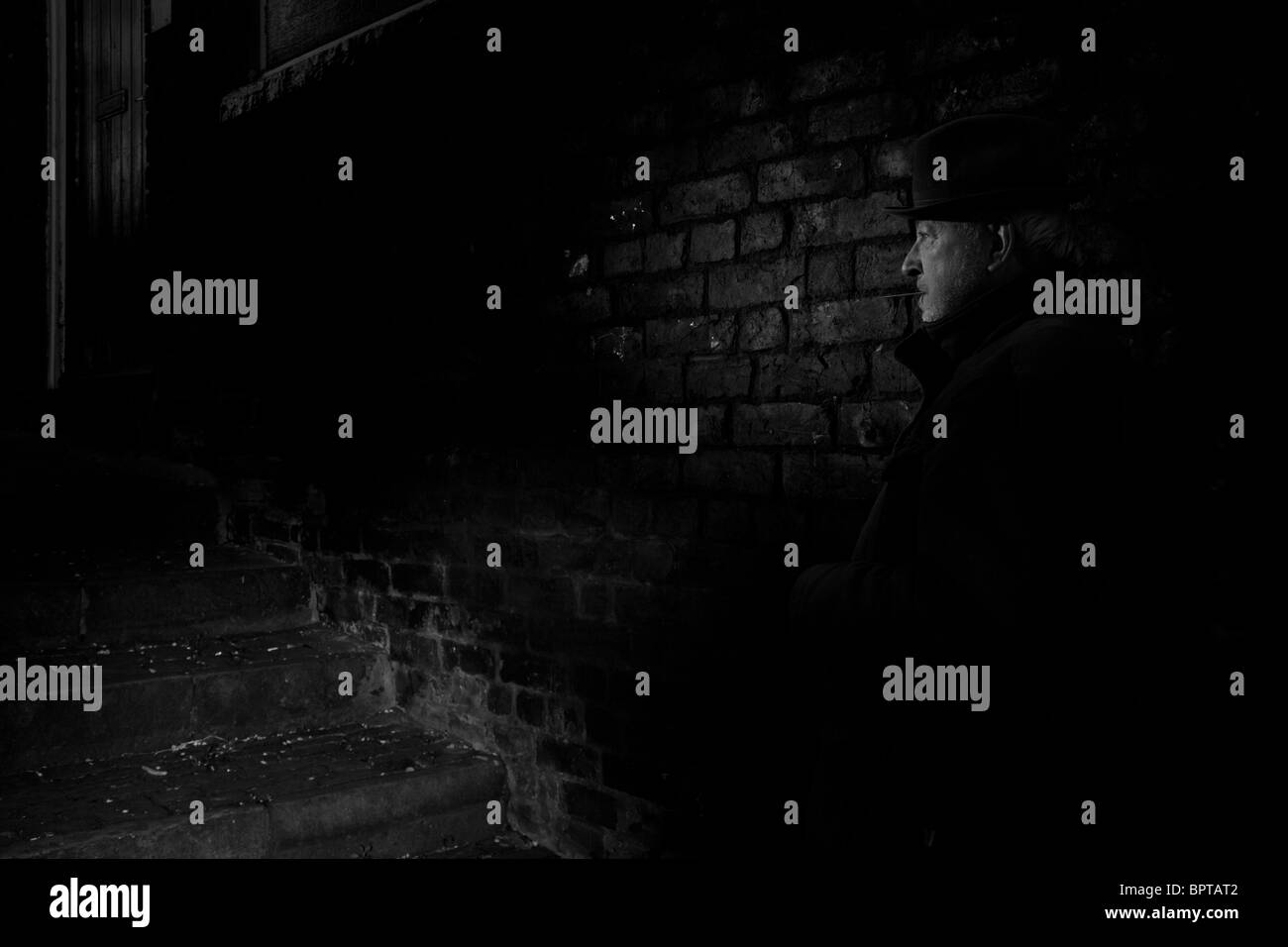 Film Noir Darstellung einen ruhigen und gefährlichen Mann wartet in einer dunklen Gasse. Stockfoto