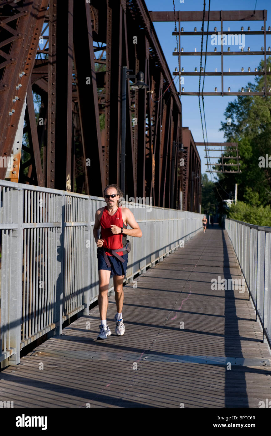 Männliche Jogger überqueren einer Eisenbahnbrücke in Laval, Quebec, Kanada Stockfoto