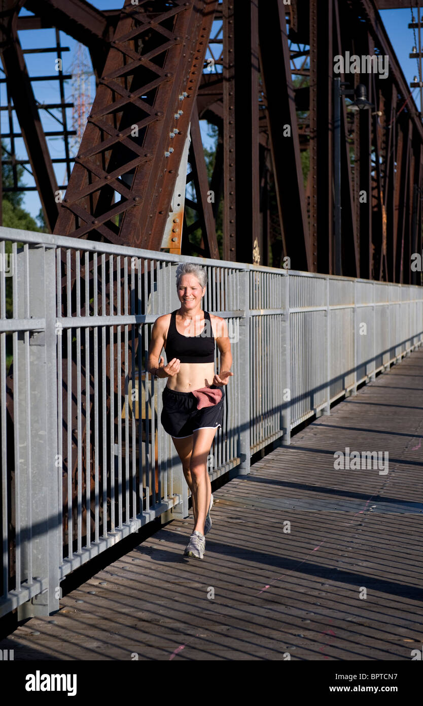 Weibliche Jogger überqueren einer Eisenbahnbrücke in Laval, Quebec, Kanada Stockfoto