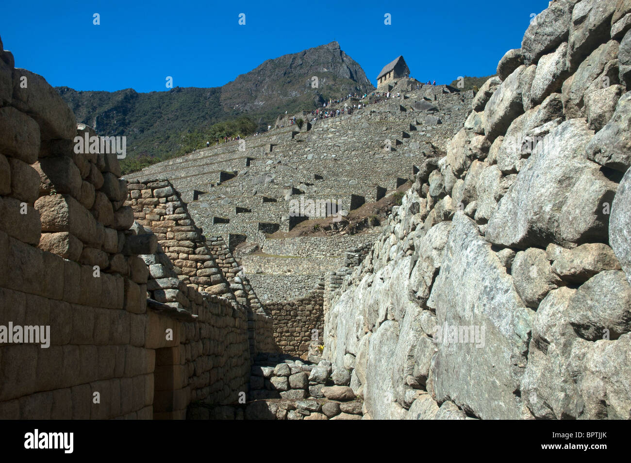 Touristen in das komplizierte Mauerwerk der zerstörten Gebäude an der alten Inka-Stadt Machu Picchu, Peru. Stockfoto