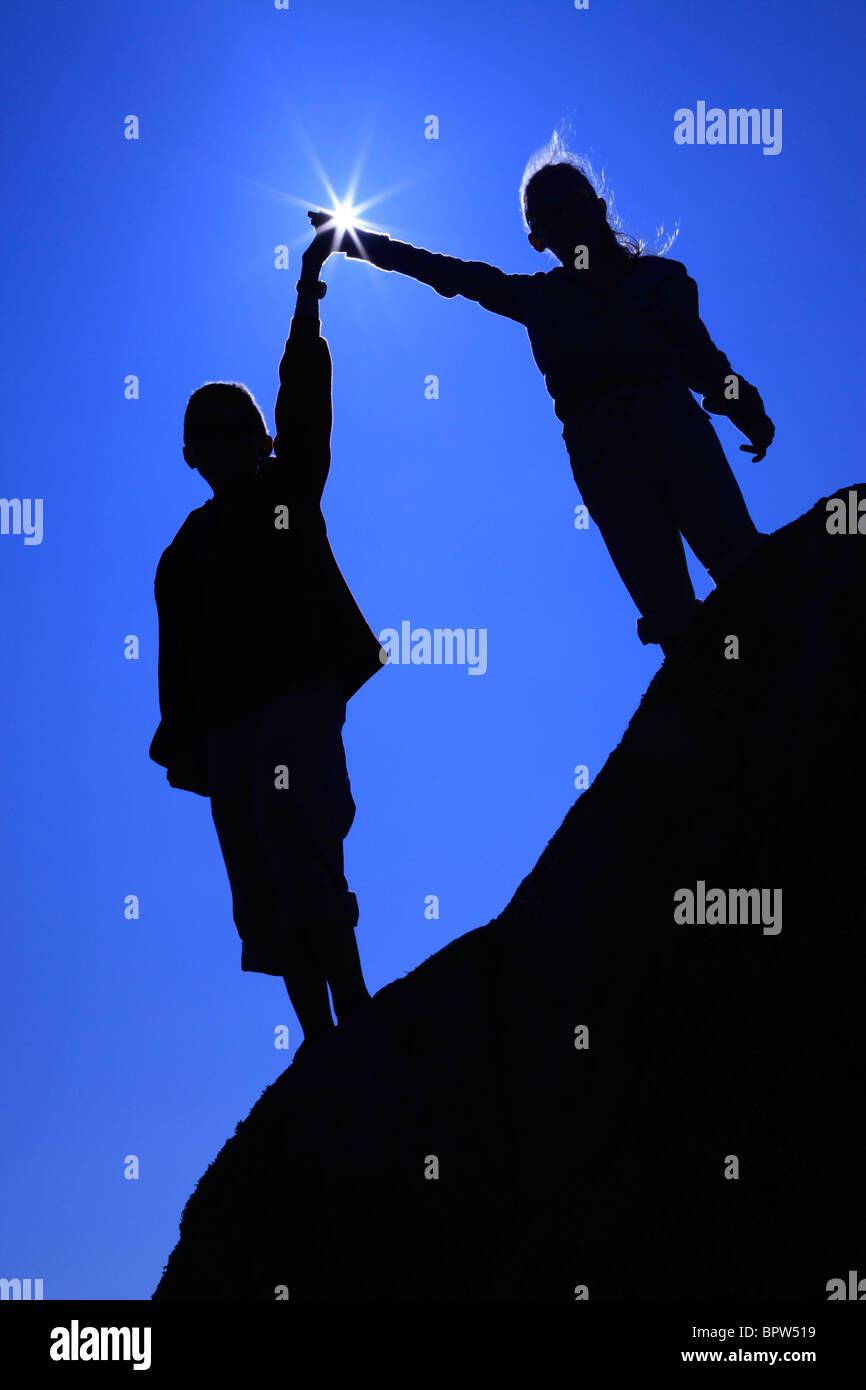 Silhouette der beiden Kinder Hand in Hand mit einem Sunstar Blendenfleck auf Herm Island genommen Stockfoto