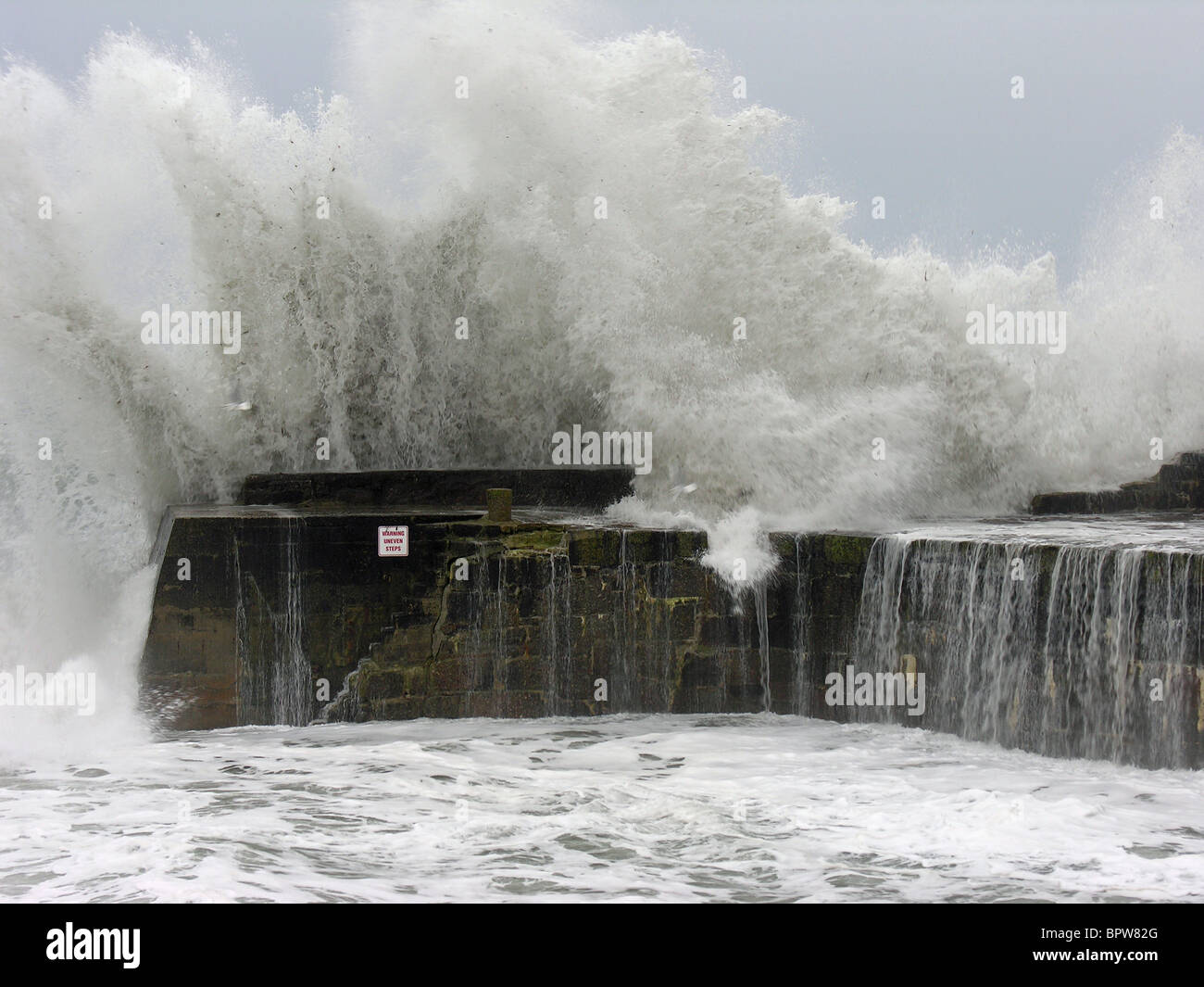 Eine riesige Welle bricht über den Deich später Cove, Cornwall, UK Stockfoto