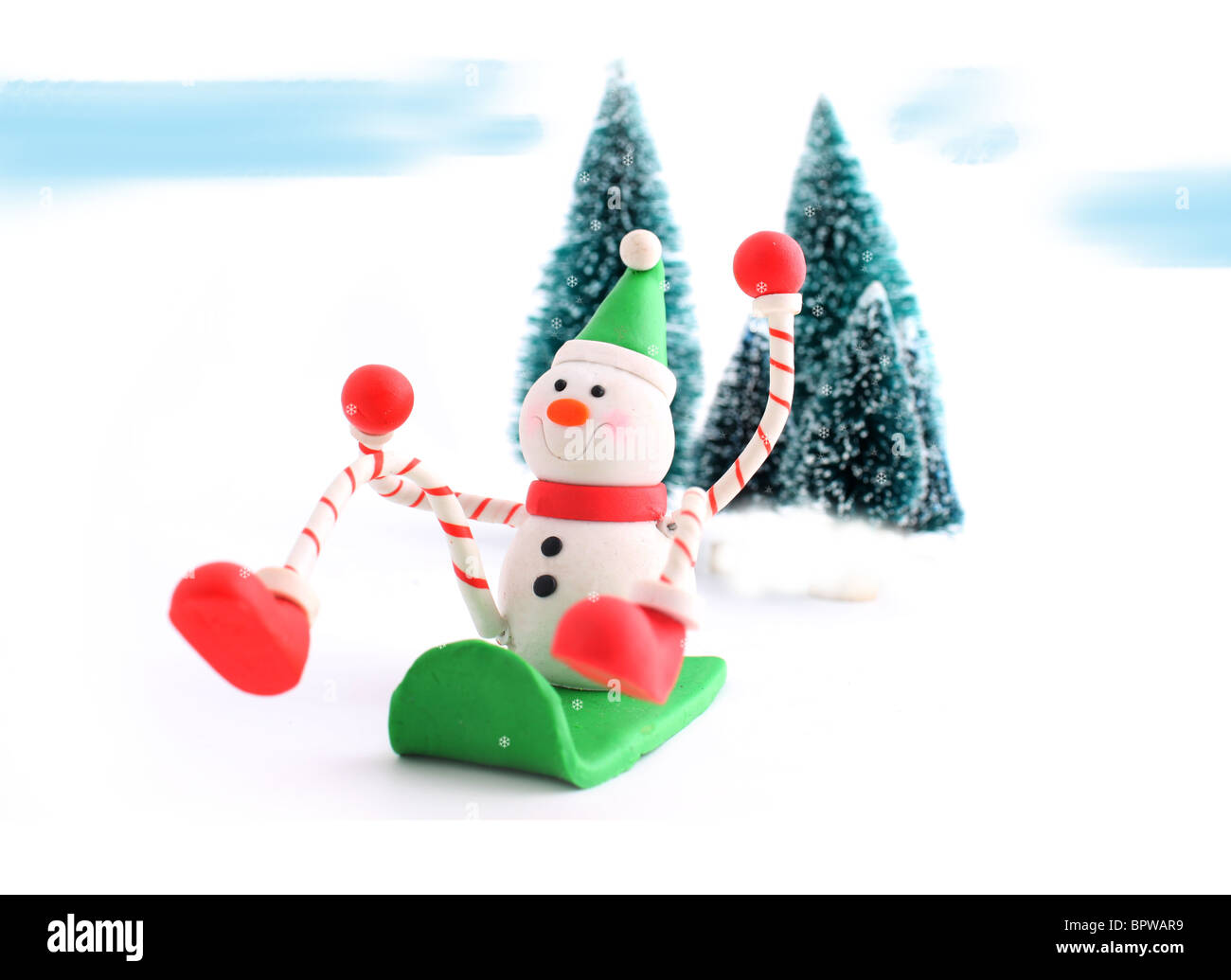 Schneemann Weihnachten Charakter Abrutschen einer Snowhill auf einem Schlitten mit Pinien im Hintergrund, ideal für eine Grußkarte Stockfoto