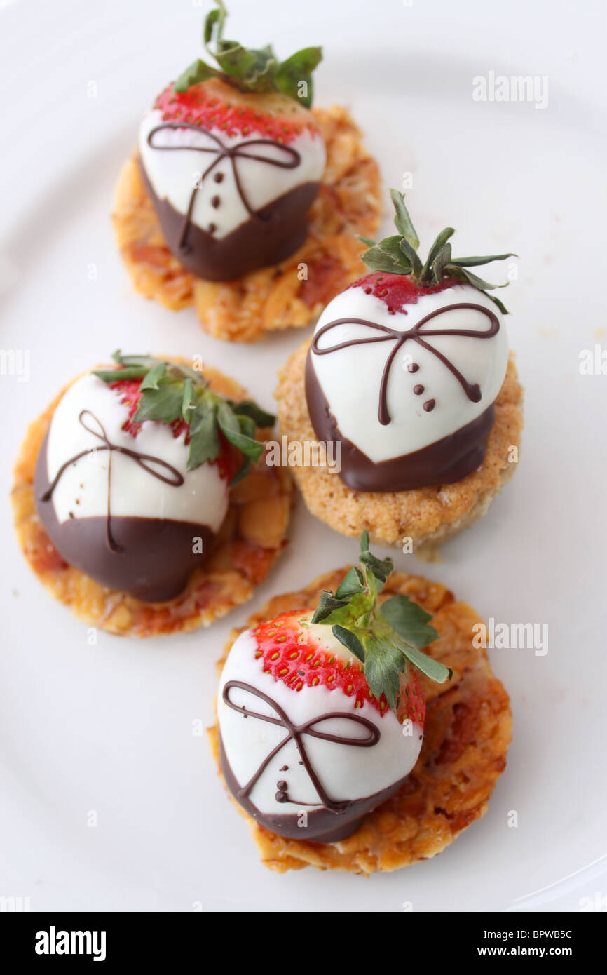 Weißer und dunkler Schokolade überzogene Erdbeeren auf Torte Leckereien und weißen Teller (geringe Schärfentiefe) Stockfoto