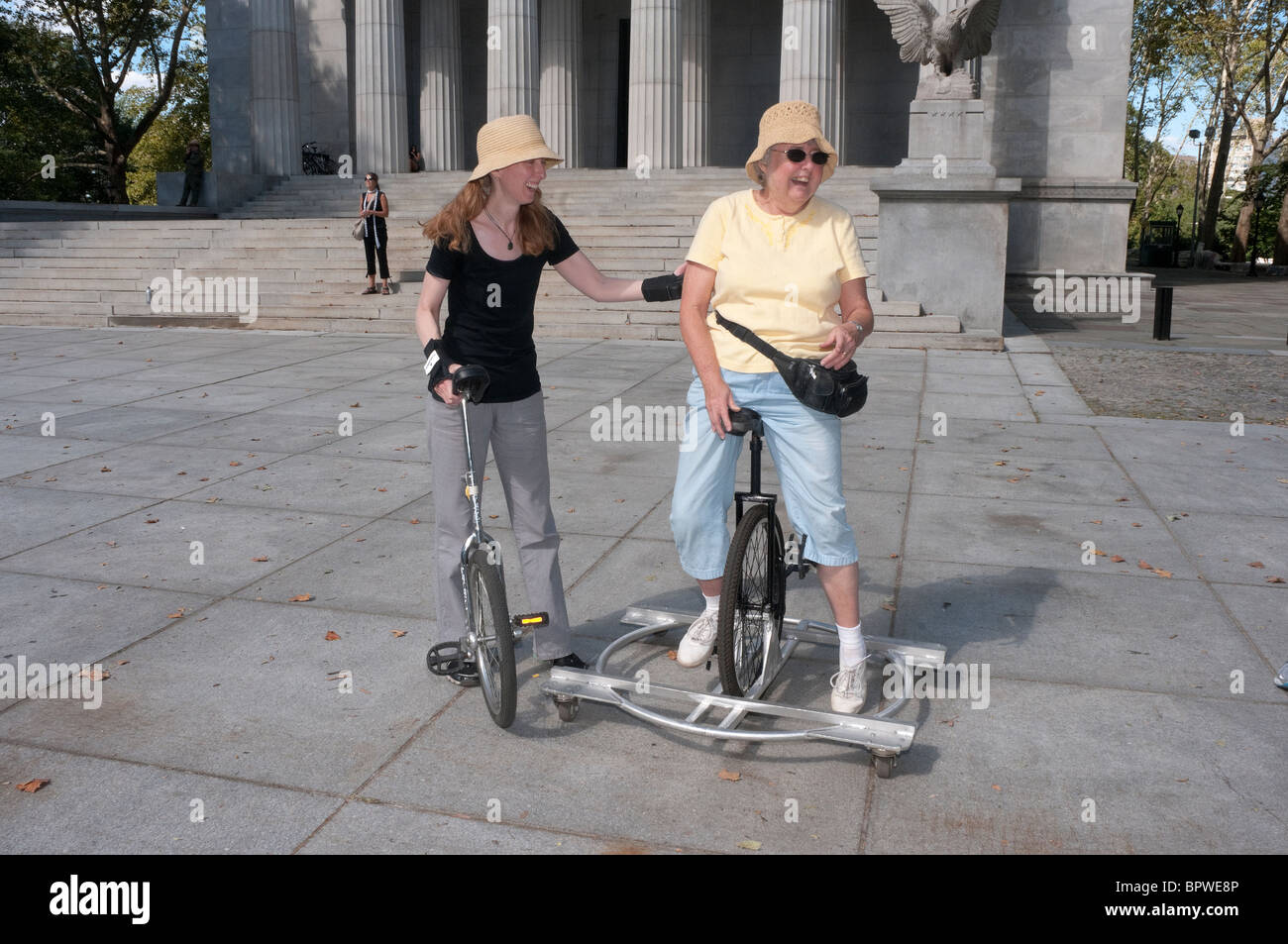 Reife Frau, die ein Einrad mit Stützrädern fahren zu lernen Stockfoto