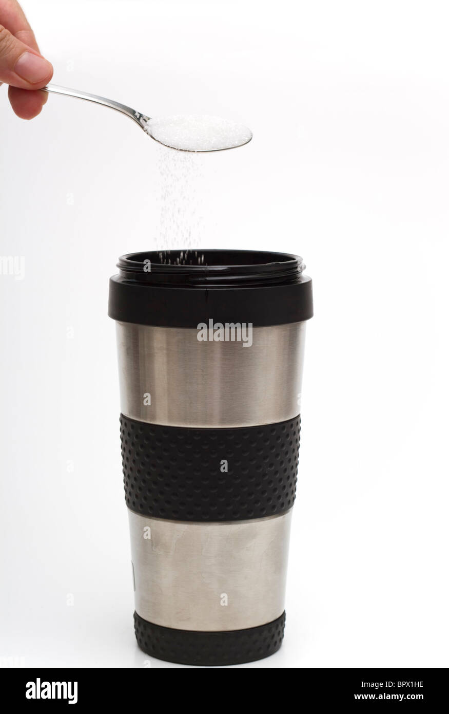 Ein heißes Getränk in einer thermischen Reisen Tasse hinzufügen einen Löffel Zucker Stockfoto