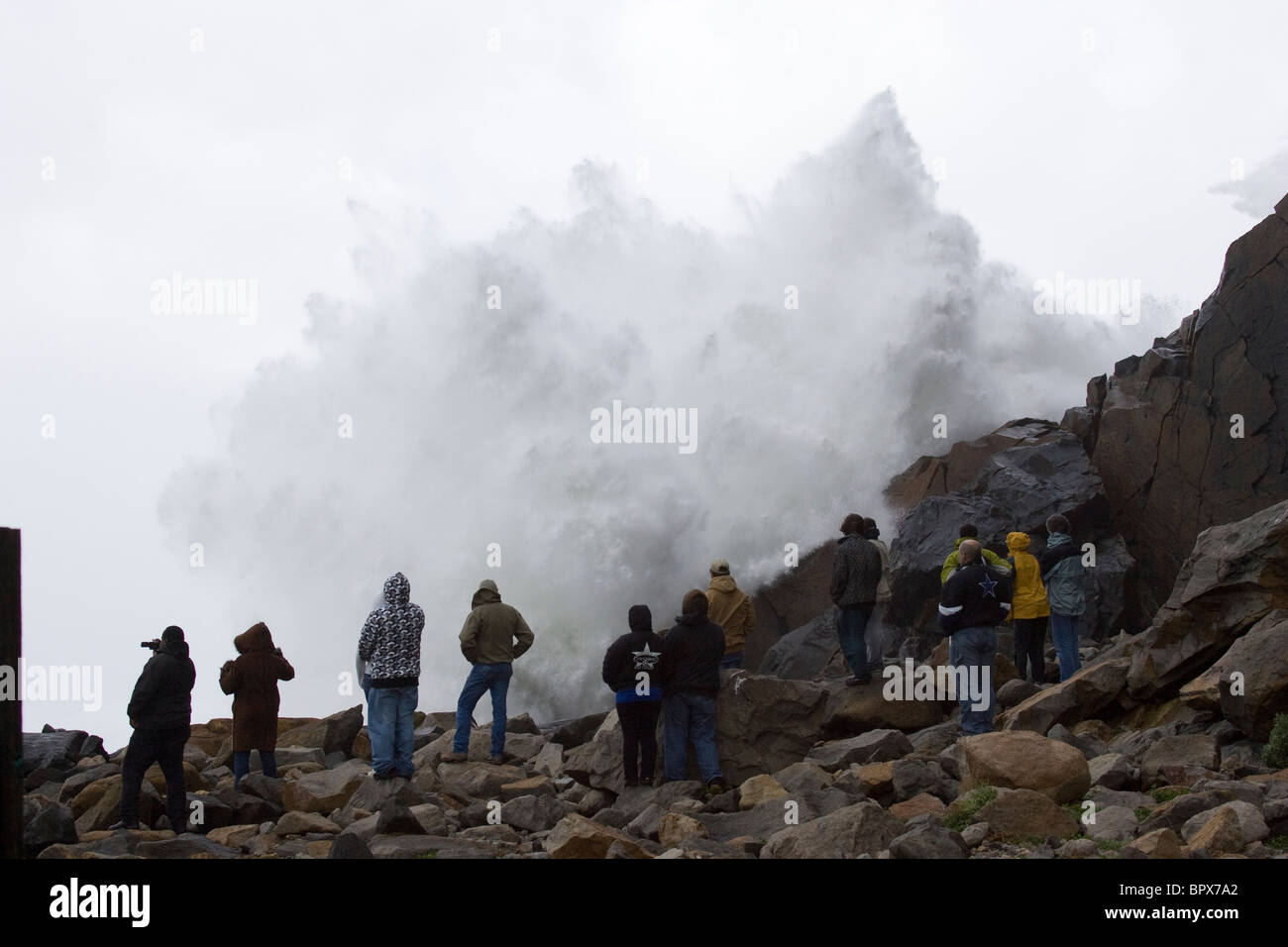 Gruppe von Menschen, die gerade einer große Sturm Welle Pause auf Felsen Stockfoto