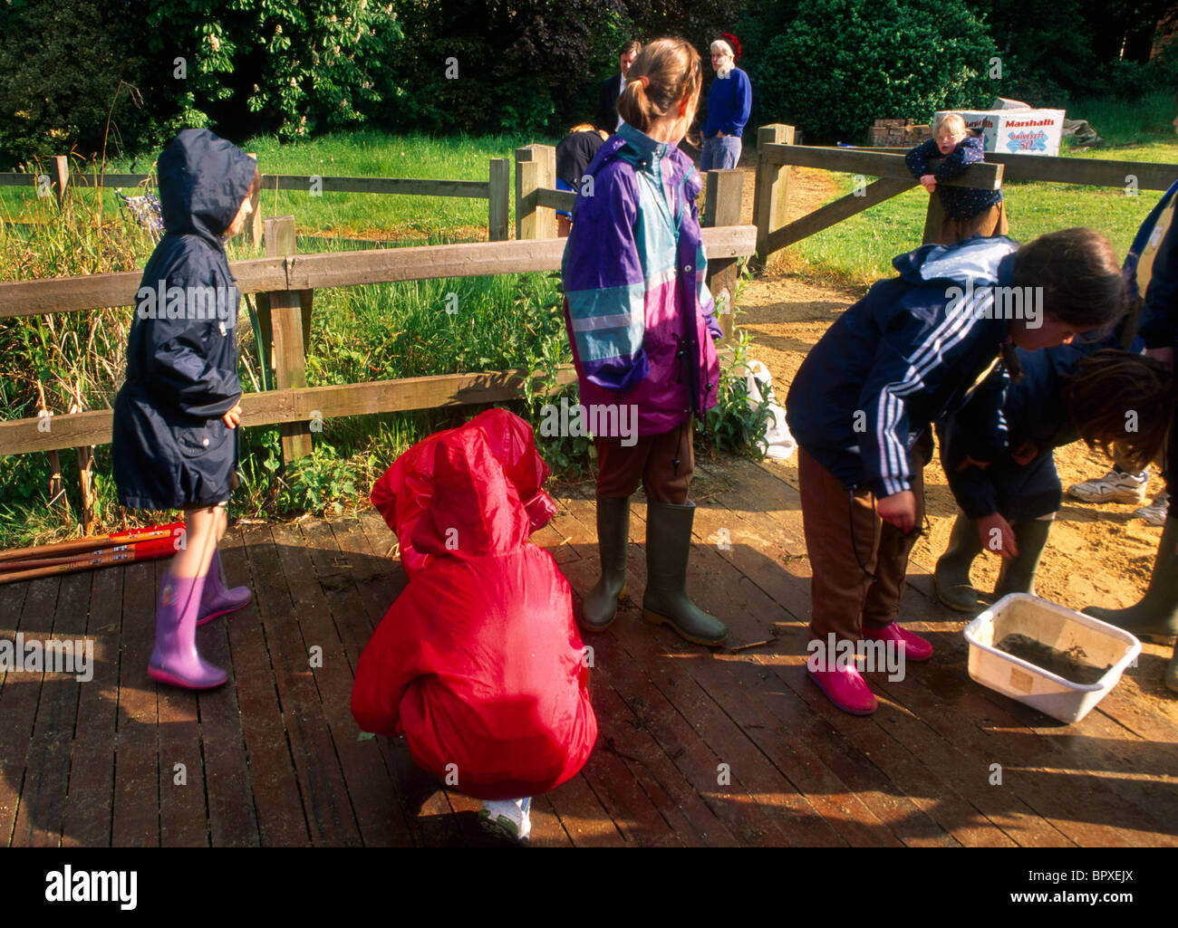 Kinder tragen Regenmäntel & Wellington Boots Teich eintauchen Stockfoto