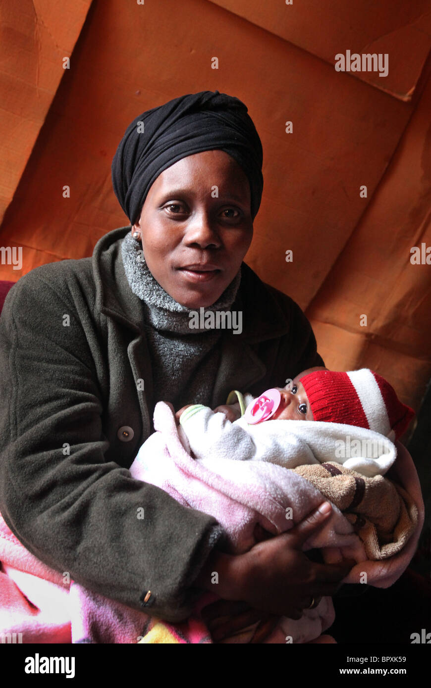 Mutter mit ihrem Baby in ihrer Hütte in einem Township in den Weinbergen von De Doorns, Western Cape, South Africa, Hex Valley Stockfoto