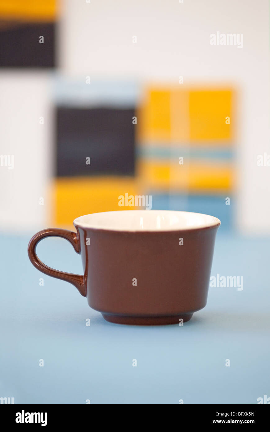 braune Kaffeetasse im Künstleratelier mit Gemälden im Hintergrund Stockfoto