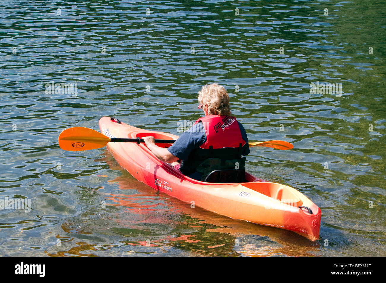 Ein senior weißen kaukasischen orange Kajak zu paddeln. Stockfoto