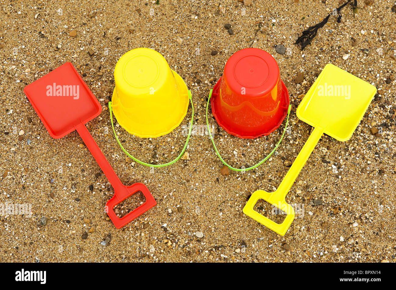 Bunte Kunststoff-Eimer und Spaten an einem Strand. Stockfoto