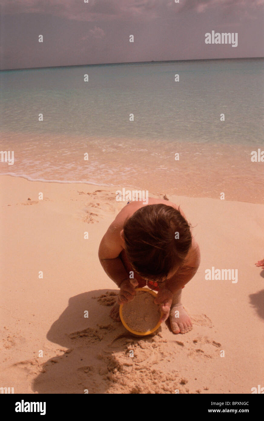 Jungen spielen mit Sand am Strand Stockfoto