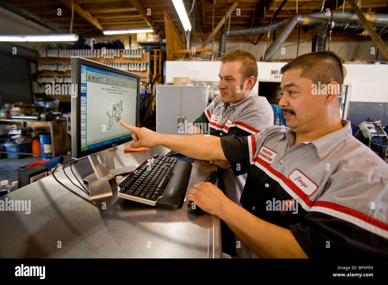 Überprüfung eine schematische Bild von einem Automotor auf einem Computermonitor, zwei Mechaniker in einer unabhängigen Südkalifornien Stockfoto