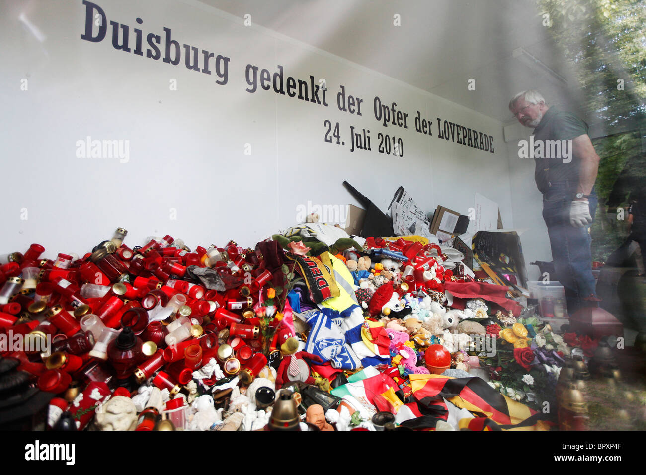 Duisburg Loveparade 2010: Glaskubus auf dem Gelände der Tragödie in die Trauer Geschenke, Kerzen und Spielzeug daran gehalten werden Stockfoto