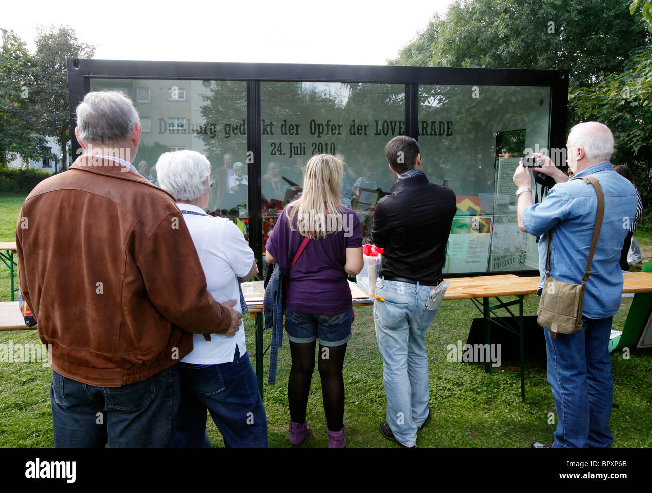 Duisburg Loveparade 2010: Glaskubus auf dem Gelände der Tragödie in die Trauer Geschenke, Kerzen und Spielzeug daran gehalten werden Stockfoto