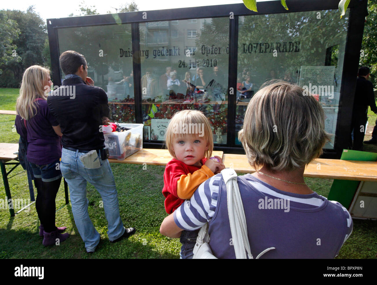 Duisburg Loveparade 2010: Glaskubus auf dem Gelände der Tragödie in die Trauer Geschenke, Kerzen und Spielzeug daran gehalten werden Stockfoto