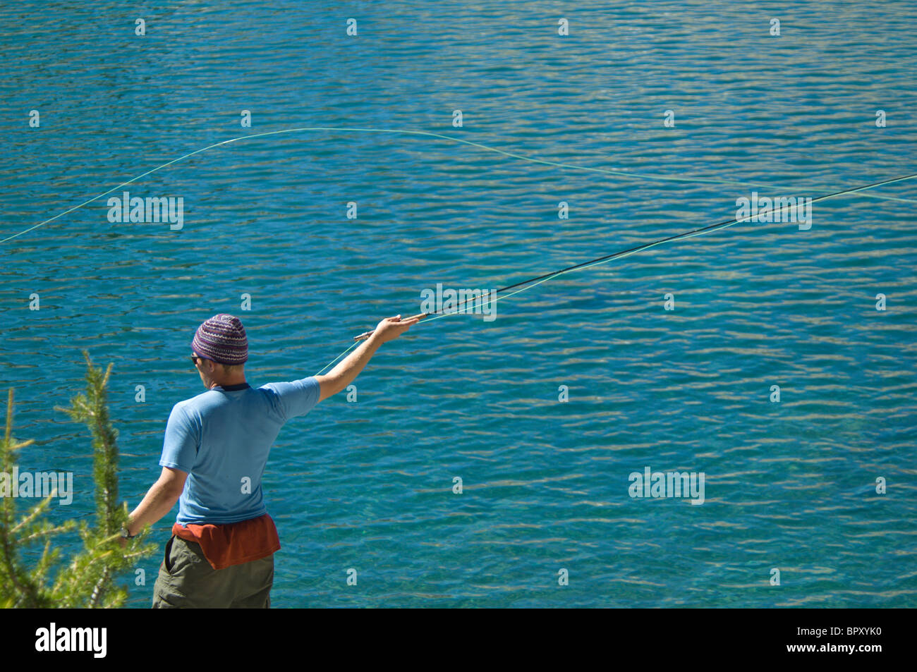 Solo-Mann Fliegenfischen über dem blauen See. Stockfoto