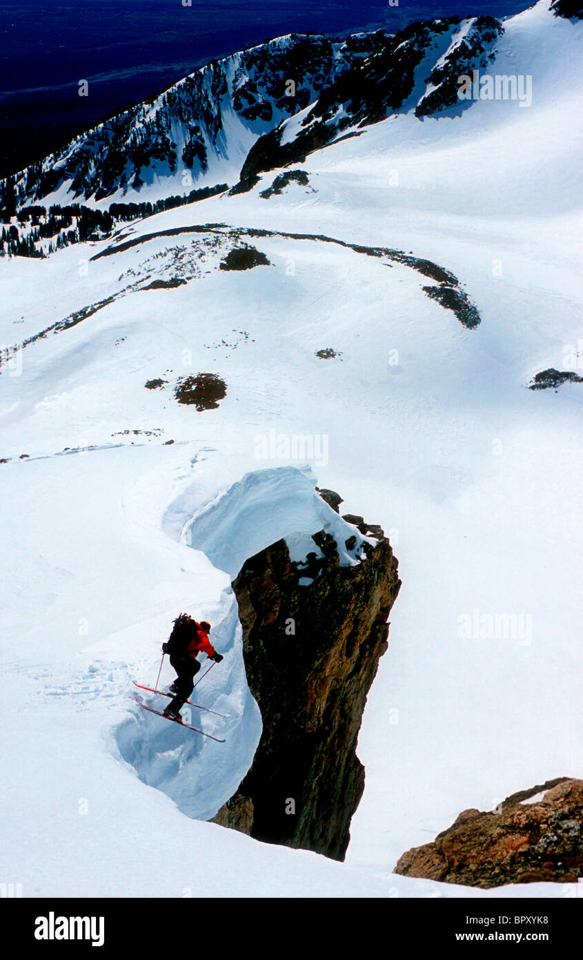 Ein Skifahrer springt in ein Couloir in den Teton. Stockfoto