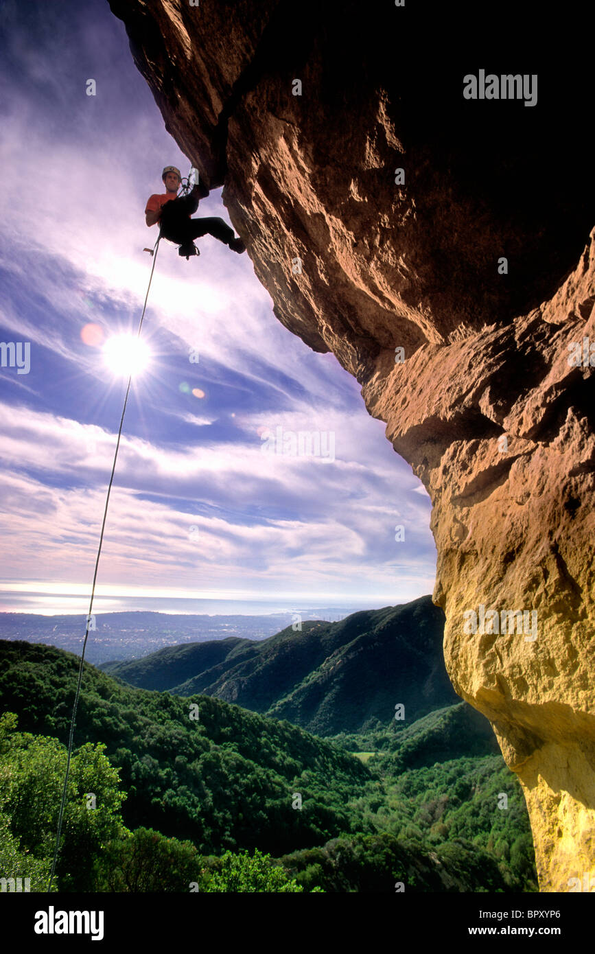 Silhouette Kletterer Abseilen überhängenden Gesicht mit grünen Canyon unten, Santa Barbara, Kalifornien (Hintergrundbeleuchtung) Stockfoto