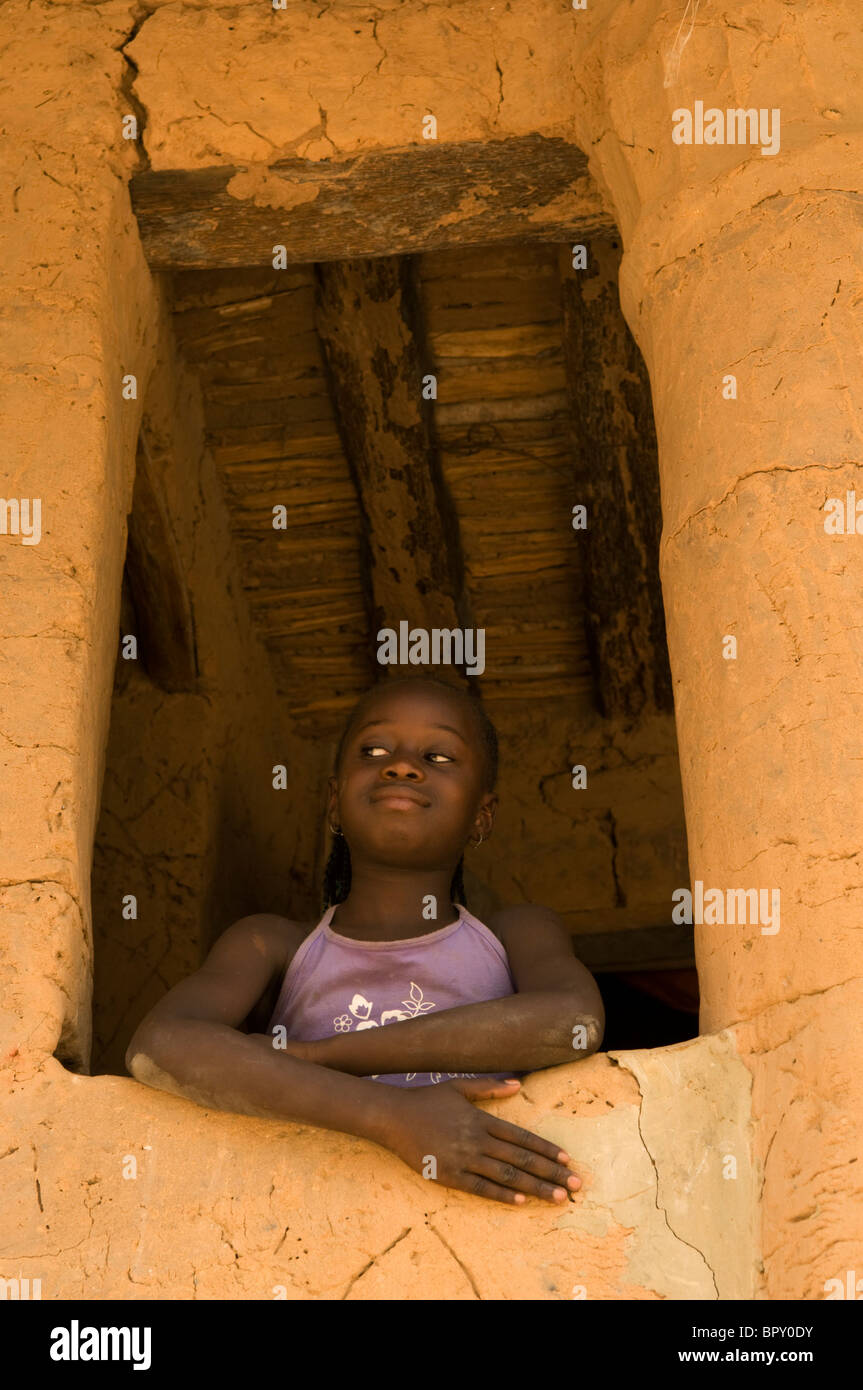 Mädchen auf der Suche durch das Fenster eines typischen Fall à Étage, M'Lomp, Casamance, Senegal Stockfoto