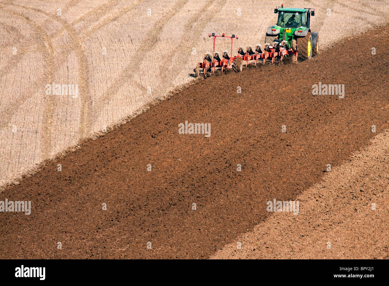 Ein Traktor und Pflug pflügen ein Feld Stockfoto
