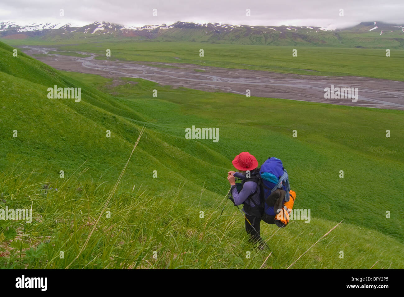 Eine Frau, Wandern auf einem Bergrücken oberhalb eines Flusses auf Umnak Island in den Aleuten. Stockfoto