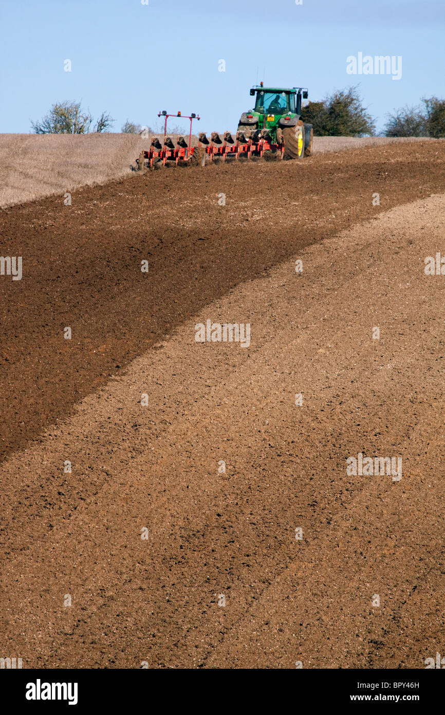Ein Traktor und Pflug pflügen ein Feld Stockfoto