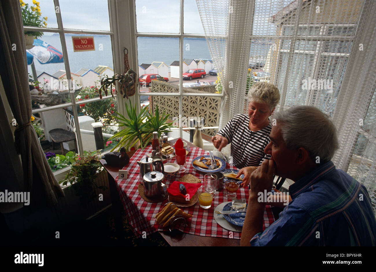 Urlaub paar genießen Sie ein komplettes englisches Frühstück im Erker von einer & Frühstückspension (B + B) in Devon Badeort. Stockfoto